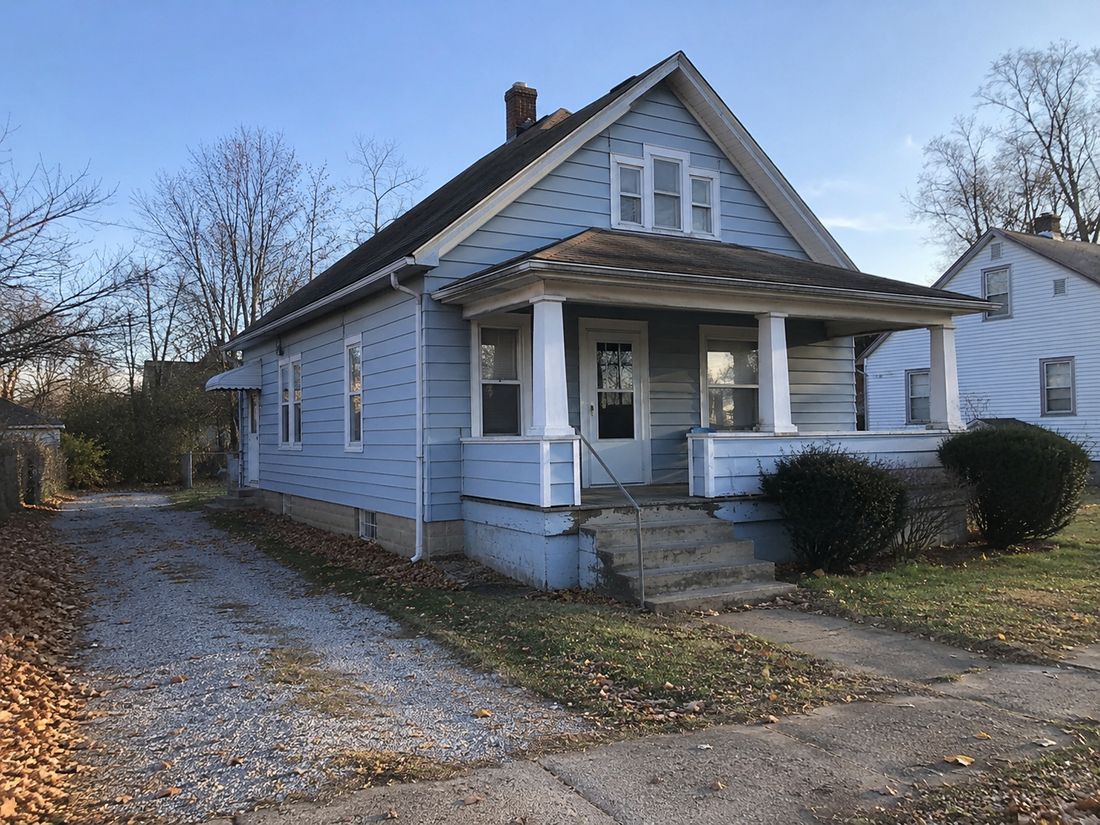 A blue craftsman home with a gravel driveway