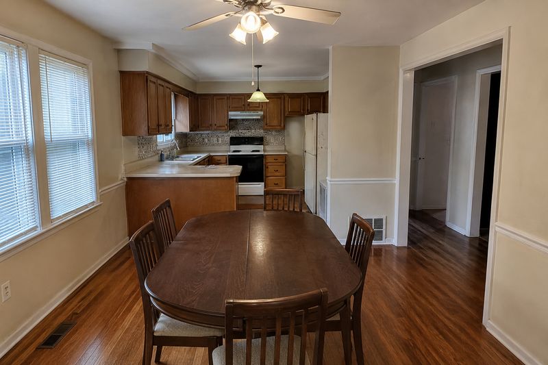 A dining room table beside an ordinary kitchen