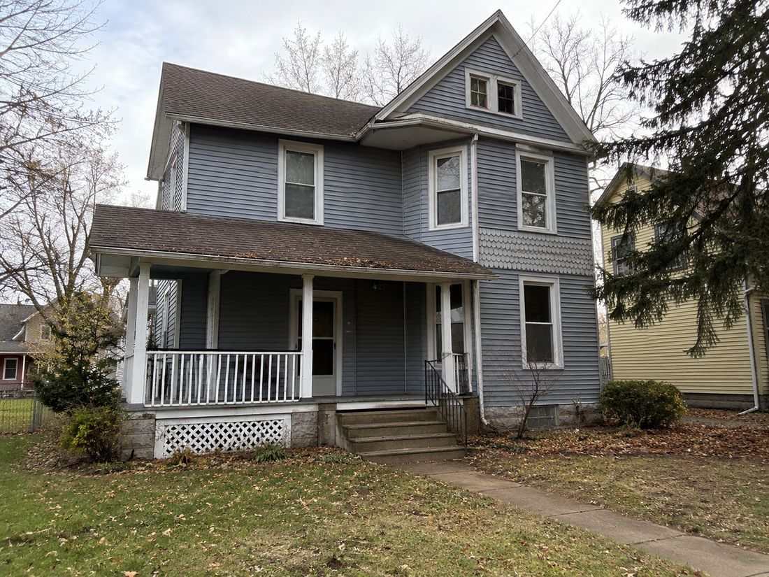 A gray farmhouse with a wraparound porch