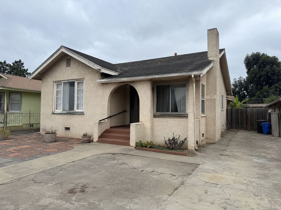 An older stucco bungalow with a concrete driveway