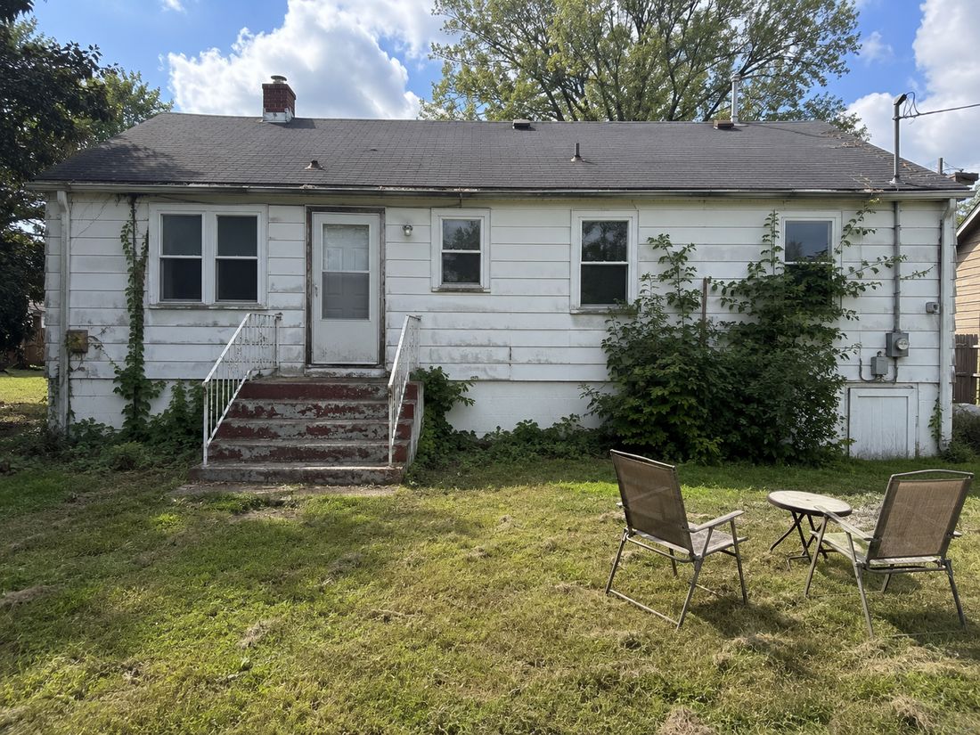 A white ranch home with worn paint, bought as-is