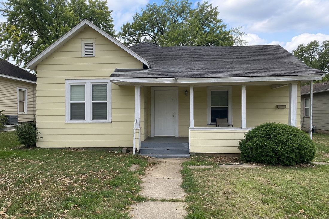 A yellow cottage with a covered front porch